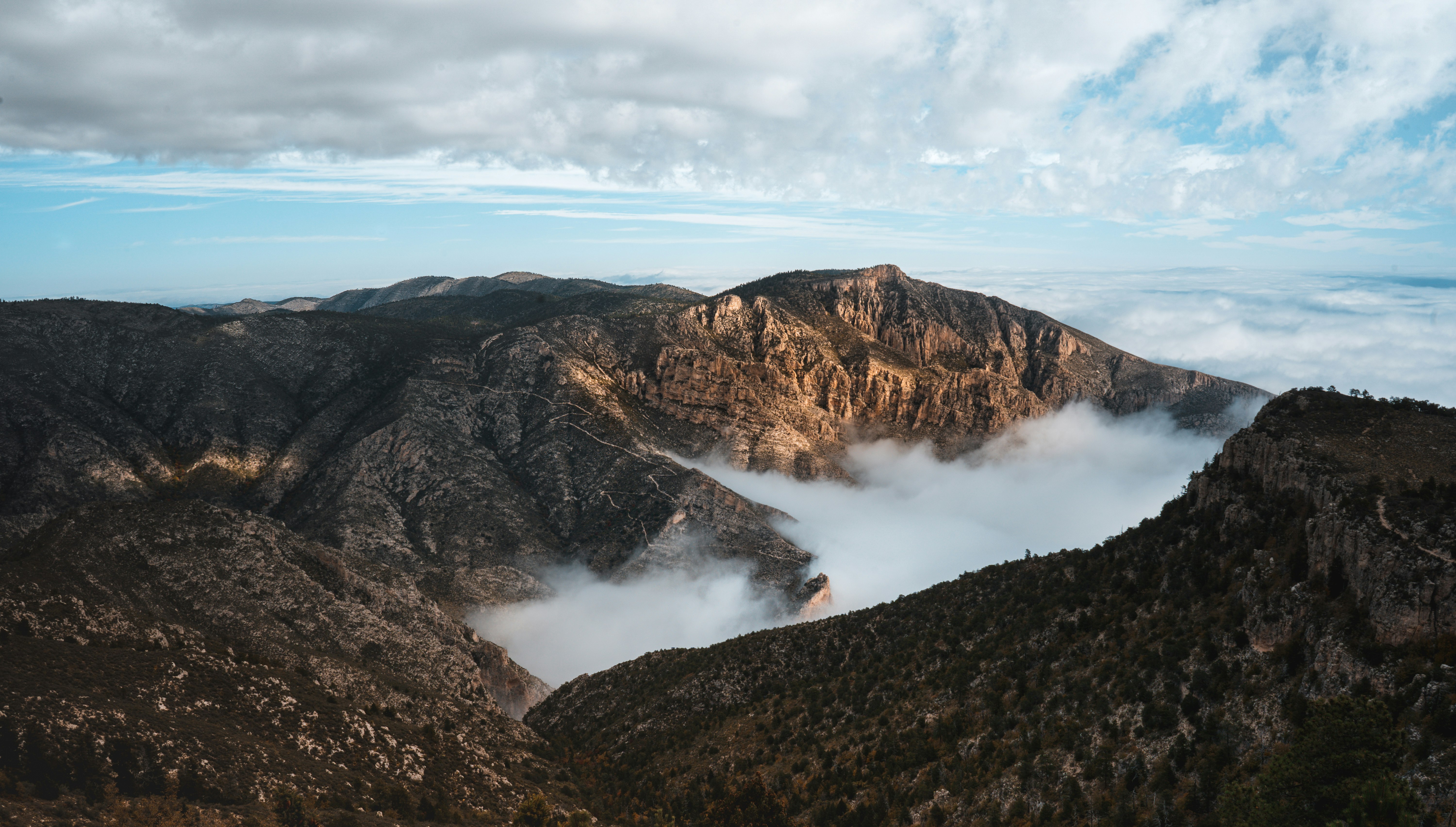 aerial photo of mountains under cloudy sky